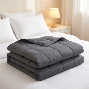 Couverture lestée grise pliée sur un lit
