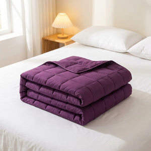 Couverture lestée violette pliée sur un lit