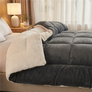 Couverture chaude réversible anthracite en velours et effet mouton sur un lit cosy