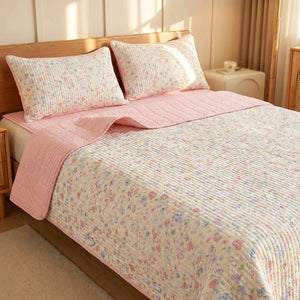 Couvre-lit matelassé fleuri pastel et envers rose sur un lit