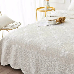 Couvre-lit matelassé blanc vue complète sur un lit avec table d'appoint dorée