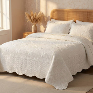 Couvre-lit matelassé blanc dans une chambre cocooning avec tête de lit en rotin