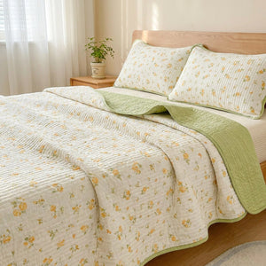 Couvre-lit fleuri jaune installé sur un lit vu de côté dans une chambre lumineuse