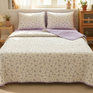 Couvre-lit matelassé à fleurs lavande et envers lilas sur un lit