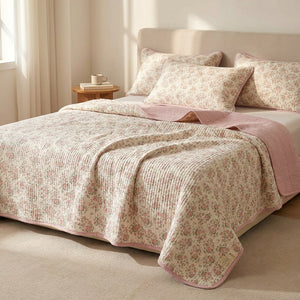 Couvre-lit matelassé imprimé floral rose dans une chambre lumineuse avec table de chevet