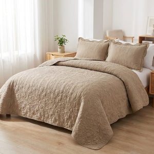 Couvre-lit matelassé taupe sur un lit fait dans une chambre lumineuse au réveil