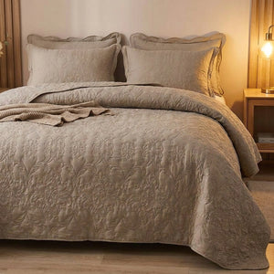 Couvre-lit matelassé taupe dans une chambre cosy avec lampe de chevet allumée