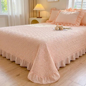Couvre-lit matelassé rose à motif de cœurs et volant sur un lit