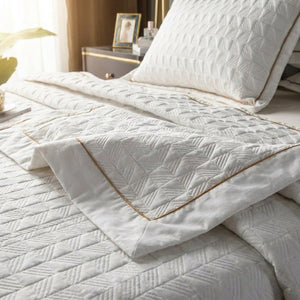 Détail du matelassage géométrique et du fin liseré doré du couvre-lit
