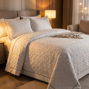 Couvre-lit matelassé et taies assorties sur un lit dans une chambre chaleureuse en soirée