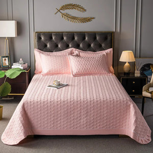 Couvre-lit matelassé rose avec deux taies assorties sur un lit