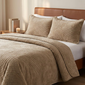 Couvre-lit matelassé velours beige dans une chambre avec tête de lit en cuir et bougie