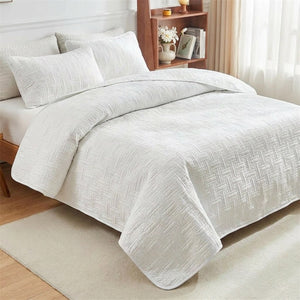 Couvre-lit matelassé blanc à motif de tissage géométrique sur un lit