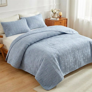 Couvre-lit matelassé bleu gris à motif de tissage géométrique sur un lit