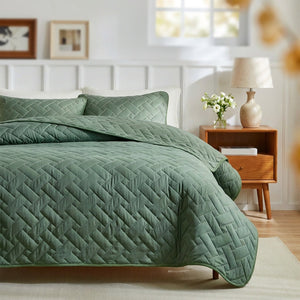 Couvre-lit matelassé vert à motif de tissage géométrique sur un lit