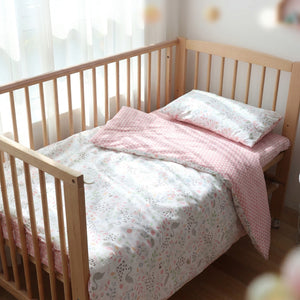 Parure de lit bébé motif cygne en coton rose posée sur un berceau