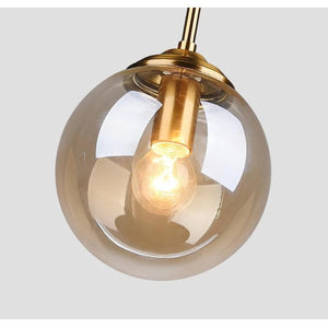 Vue dessous suspension globe en verre ambre revelant monture laiton et ampoule filament