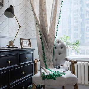 Rideau boho en lin floral à pompons verts devant une fenêtre