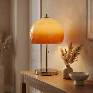 Lampe à poser champignon orange allumée sur une console d'entrée décorée