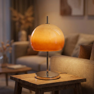 Lampe à poser champignon en verre orange allumée sur une table près d'un canapé