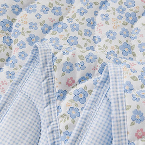 Détail du tissu matelassé de la couette d'été à fleurs bleues et de son envers à carreaux vichy