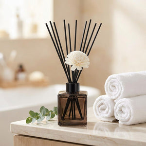Diffuseur à bâtonnets posé sur une étagère de salle de bain avec serviettes et eucalyptus