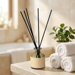 Diffuseur de parfum à bâtonnets sur une étagère de salle de bain avec serviettes roulées