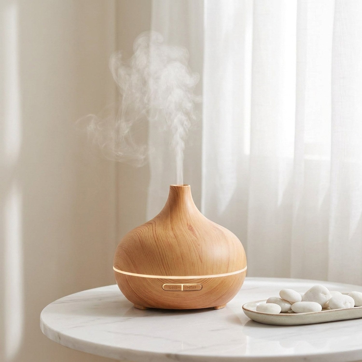 Diffuseur d'arômes grain de bois sur table marbre blanc avec rideaux voilages, galets blancs, brume légère