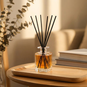 Diffuseur de parfum à bâtonnets dans un flacon en verre posé sur un plateau dans un salon chaleureux