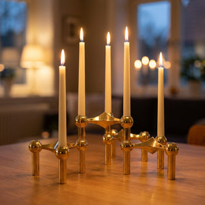 Chandelier modulaire en métal doré avec bougies fines allumées sur une table