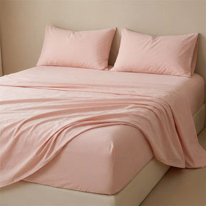 Drap plat rose poudré en coton fait sur un lit avec oreillers assortis