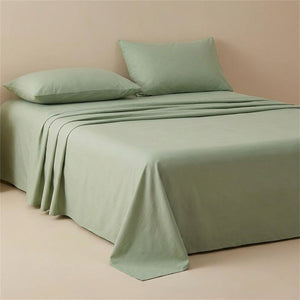 Drap plat vert sauge en coton fait sur un lit avec oreillers assortis