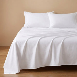 Drap plat blanc en coton fait sur un lit avec oreillers assortis