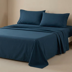 Drap plat bleu foncé en coton fait sur un lit avec oreillers assortis