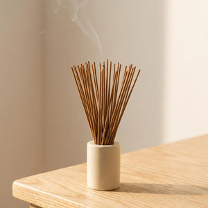 Bâtons d'encens dans un porte-encens blanc sur bois naturel
