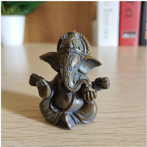Figurine Ganesha bronze sur bureau en bois avec livres et plante