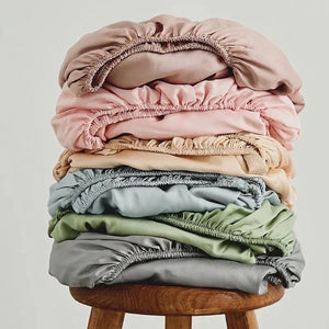 Pile de draps-housses en coton pliés dans plusieurs coloris