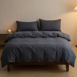 Parure de lit unie gris foncé posée sur un lit dans une chambre moderne épurée