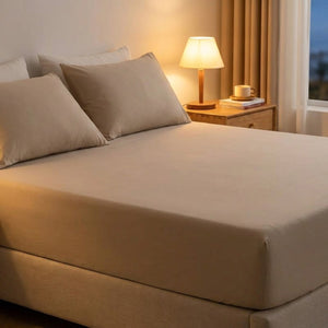 Drap-housse beige sur un lit dans une chambre moderne avec lampe de chevet allumée