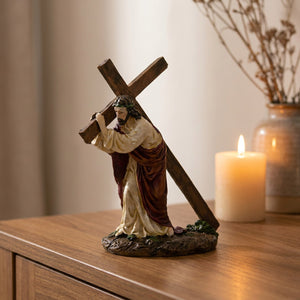 Statue de Jésus portant la croix en résine peinte à la main posée sur une console en bois