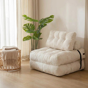 Chaise pliante convertible blanche en velours côtelé posée dans un salon lumineux avec plante verte