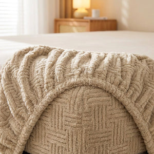 Coin replié d'un drap-housse beige en peluche gaufrée montrant l'élastique