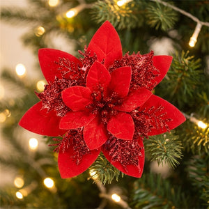 Fleur artificielle de poinsettia à paillettes scintillantes posée sur une branche de sapin de Noël