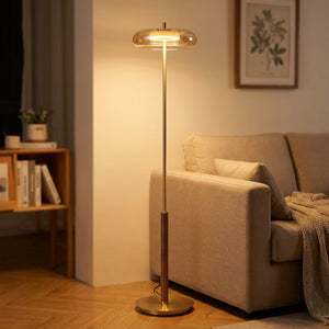 Lampadaire vintage en laiton et noyer abat-jour verre ambré allumé près d'un canapé