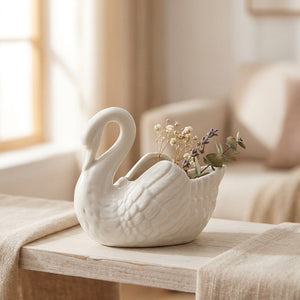 Vase cygne en céramique blanc garni de fleurs séchées sur une étagère en bois