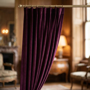 Rideau en velours prune suspendu à une fenêtre dans un intérieur raffiné