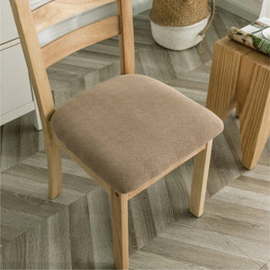 Housse de siège de chaise beige sur une chaise en bois dans un intérieur lumineux