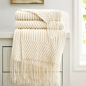 Plaid tricoté crème à franges posé sur un meuble près d une fenêtre