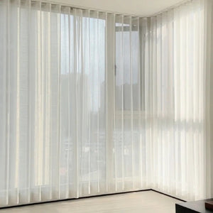 Rideau voile blanc effet vague habillant un angle de fenêtre dans un salon lumineux