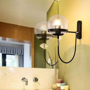 Applique murale boule de verre noire et dorée installée près d'un miroir de salle de bain